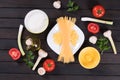 Raw pasta, tomatoes,mushrooms, flour and egg on black wooden table background Royalty Free Stock Photo