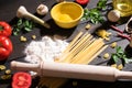 Raw pasta, tomatoes,mushrooms, flour and eggs on black wooden table background, top view. Royalty Free Stock Photo