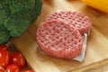 Raw patties of minced meat on a wooden board