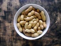 Raw peanuts on a plate, wooden background