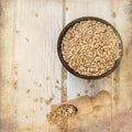 Raw pearl barley in a bowl and wooden spoon