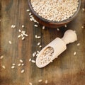 Raw pearl barley in a bowl and wooden spoon