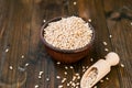 Raw pearl barley in a bowl and wooden spoon