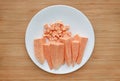 Raw peeled and chopped sweet potatoes in white plate on wood board background Royalty Free Stock Photo