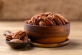 Raw peeled pecan nuts in wooden bowl on wooden background