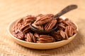 Raw peeled pecan nuts in wooden plate with spoon