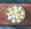 Raw peeled potatoes in a round bowl on an old cutting board on rustic wooden table close-up Royalty Free Stock Photo