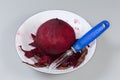 Raw peeled red beetroot and peeler among peelings in bowl