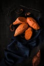 Raw peeled sweet potatoes on the wooden black table top view Royalty Free Stock Photo