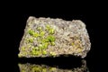 Raw peridot or olivine mineral stone in front of black background