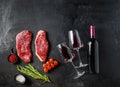 Raw picanha beef cuts with glasses of red wine, flat laym over black background space for text. Big size