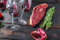 Raw picanha beef steak with rosemary, spicy chili oil, pomegranate and glass of red wine, on old dark wooden table side view, Royalty Free Stock Photo