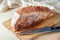 Raw piece of pork meat with fat rind rubbed with mustard and spices on a wooden kitchen board, ready prepared for the oven for a