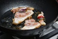 A raw piece of pork meat is fried in fat and hot oil Royalty Free Stock Photo