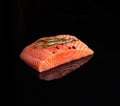 Raw piece of salmon fillet with a sprig of rosemary on a black reflective background Royalty Free Stock Photo