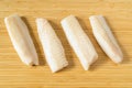 Raw pieces of frozen cod fish loins on wooden cutting board