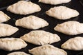 Raw pies lying on a black steel baking sheet. Close-up view