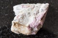 Raw pink Tourmaline in feldspar on black granite