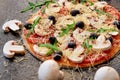 Raw pizza on the black background close up decorated with white mushrooms. Vegetarian pizza with cheese, vegetables, black olives Royalty Free Stock Photo
