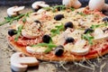 Raw pizza on the black background close up. Vegetarian pizza with cheese, vegetables, mushrooms, black olives and fresh rucola Royalty Free Stock Photo