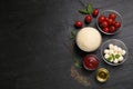 Raw pizza dough and other ingredients on black table, flat lay. Space for text Royalty Free Stock Photo