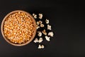 Raw popcorn in wooden bowl on black background and space for text, top view Royalty Free Stock Photo