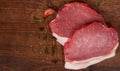 Raw pork chop steak and garlic, pepper on the brown wooden table background. rustic kitchen table with copy space. Royalty Free Stock Photo