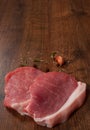 Raw pork chop steak and garlic, pepper on the brown wooden table background. rustic kitchen table with copy space. top view. Royalty Free Stock Photo