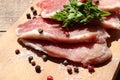 Raw pork chops on cutting board. Uncooked meat steaks for grilling with spices, pepper, salt and greens on wooden background. Top