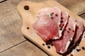 Raw pork chops on cutting board. Uncooked meat steaks for grilling with spices, pepper, salt and greens on wooden background. Top
