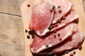 Raw pork chops on cutting board. Uncooked meat steaks for grilling with spices, pepper, salt and greens on wooden background. Top