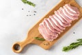 Raw pork fillet with spices, garlic and rosemary on a wooden board on white background. Top view, copy space Royalty Free Stock Photo