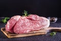 Raw pork ham, salt and rosemary on a cutting board on a dark background Royalty Free Stock Photo