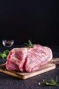 Raw pork ham, salt and rosemary on a cutting board on a dark background. Vertical view Royalty Free Stock Photo