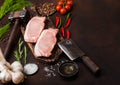 Raw pork loin chops on old chopping board with salt and pepper and vintage meat hatchets and hammer on rusty background.Red pepper Royalty Free Stock Photo