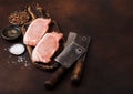 Raw pork loin chops on old vintage chopping board with knife and fork on rusty background. Salt and pepper with fresh rosemary and Royalty Free Stock Photo