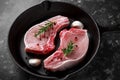 Raw Pork Loin chops in rustic skillet, pan with rosemary, garlic, pepper. top view. background Royalty Free Stock Photo