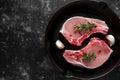 Raw Pork Loin chops in rustic skillet, pan with rosemary, garlic, pepper. top view. background Royalty Free Stock Photo