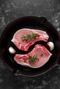 Raw Pork Loin chops in rustic skillet, pan with rosemary, garlic, pepper. top view. background Royalty Free Stock Photo