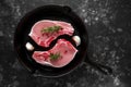 Raw Pork Loin chops in rustic skillet, pan with rosemary, garlic, pepper. top view. background Royalty Free Stock Photo