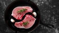 Raw Pork Loin chops in rustic skillet, pan with rosemary, garlic, pepper. top view. background Royalty Free Stock Photo