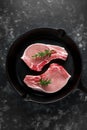 Raw Pork Loin chops in rustic skillet, pan with rosemary. top view. background Royalty Free Stock Photo