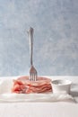 Raw pork loin on a fork. Pieces of meat impaled on a fork with spices. On parchment and blue background