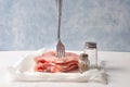 Raw pork loin on a fork. Pieces of meat impaled on a fork with spices. On parchment and blue background