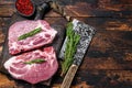 Raw pork loin steaks with herbs on a cutting board with meat cleaver. Dark wooden background. Top view. Copy space Royalty Free Stock Photo