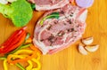 raw pork in marinade, on a cutting board with tomatoes branch, knife for meat and seasonings border ,place text wooden rustic Royalty Free Stock Photo