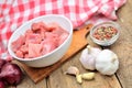 Raw pork meal diced in a bowl, garlic, onion and pepper, checkered red tablecloth in the background