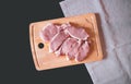 Raw pork meat. Fresh steaks on cutting board on dark background. Royalty Free Stock Photo