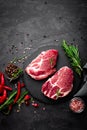 Raw pork meat. Fresh steaks on slate board on black background Royalty Free Stock Photo