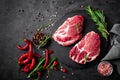 Raw pork meat. Fresh steaks on slate board on black background Royalty Free Stock Photo